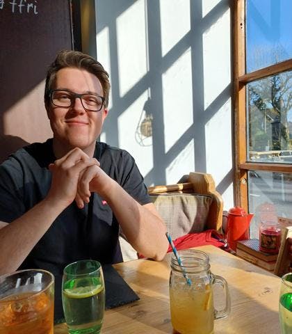 Dan Spratling sitting in a bar window with a drink, smiling